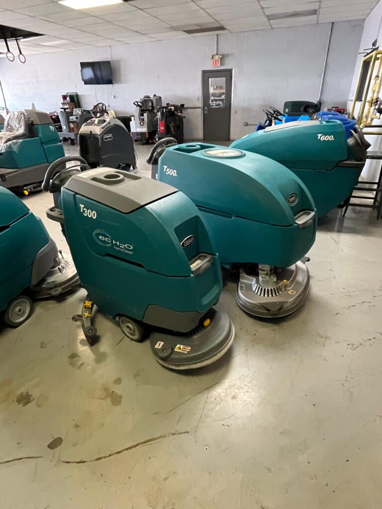 PowerKleen showroom featuring Tennant T300, T500, and T600 commercial floor scrubber machines ready for industrial cleaning applications and service support.