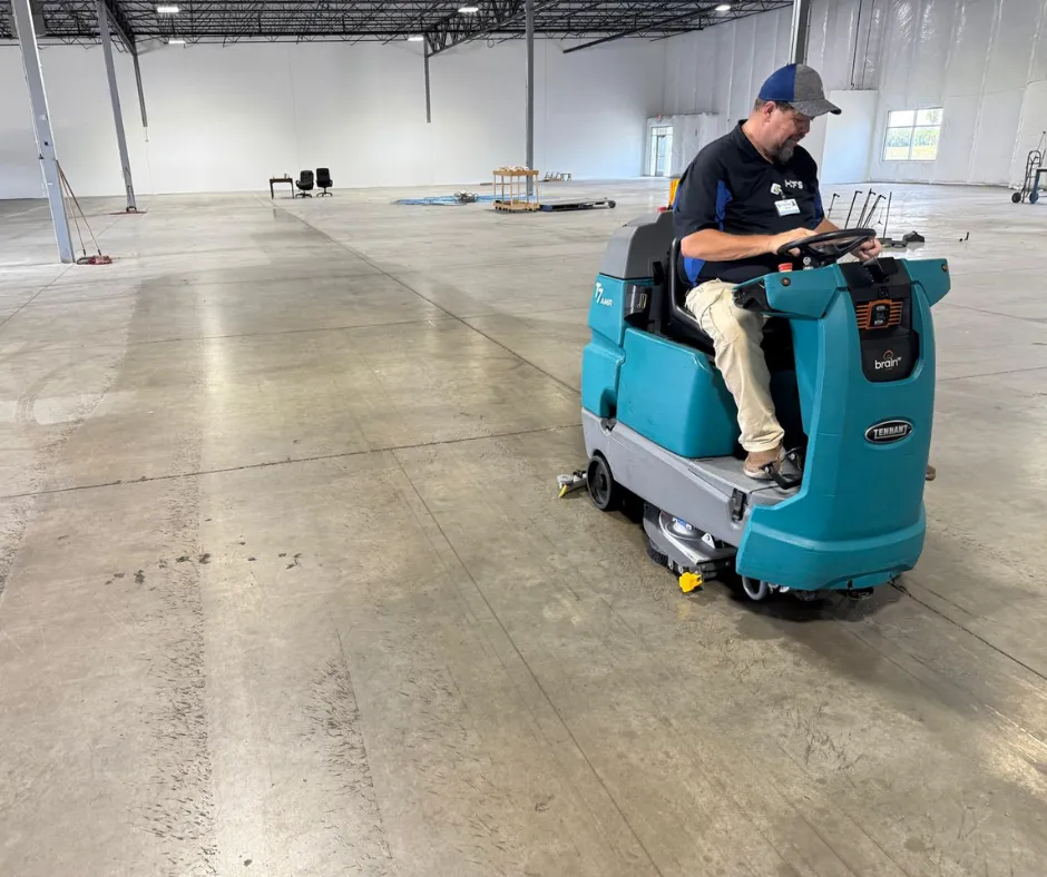 Operator using a Tennant T7 AMR ride-on floor scrubber to clean polished concrete floors inside a large commercial warehouse, demonstrating efficient industrial floor cleaning performance in wide open spaces.