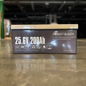 A Power Queen 25.6V 200Ah lithium battery specifications label, supplied by Robey's PowerKleen, sitting on a warehouse concrete floor.